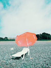 Orange umbrella on beach against sky