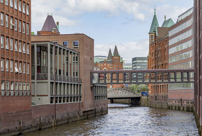 View of buildings by river against sky in city