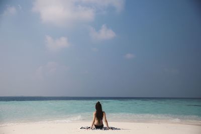 Rear view of woman on beach against sky