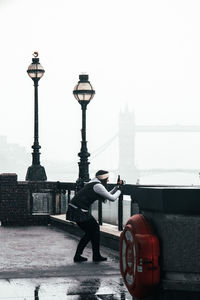 Man on street against sky in city