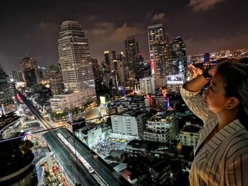 High angle view of woman and buildings against sky at night