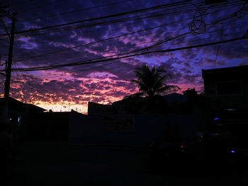 Silhouette trees and buildings against sky at night