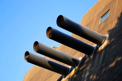 Low angle view of pipes against blue sky