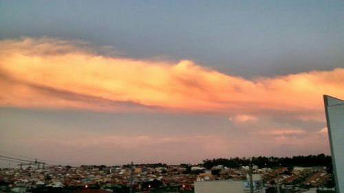 Cityscape against cloudy sky at sunset