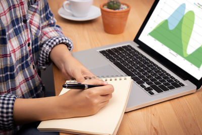 Midsection of man using laptop on table