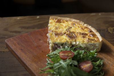 High angle view of savory pie slice with salad on wooden plate