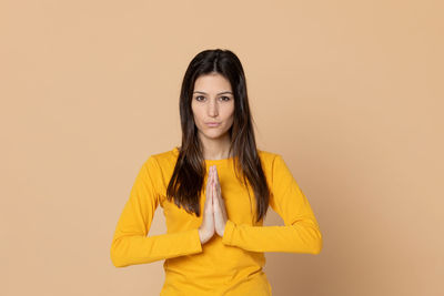 Portrait of woman standing against yellow background