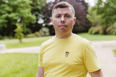 Portrait of young man standing against trees