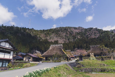 Houses by trees and buildings against sky