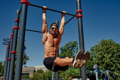 Low angle view of young man exercising on field