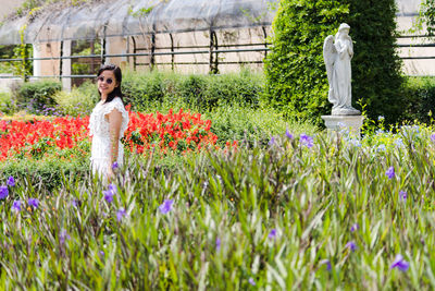 Woman standing by flowering plants on field