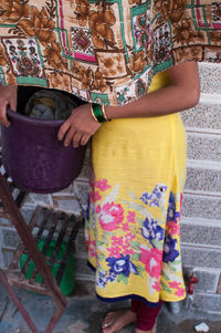 Midsection of woman holding umbrella standing outdoors