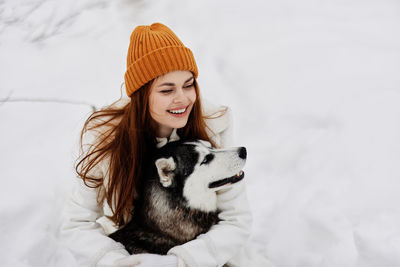 Portrait of young woman with dog on snow