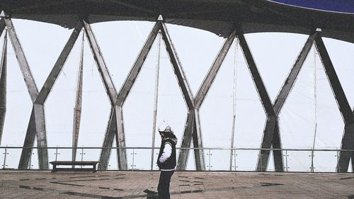 Man standing on bridge over sea against sky