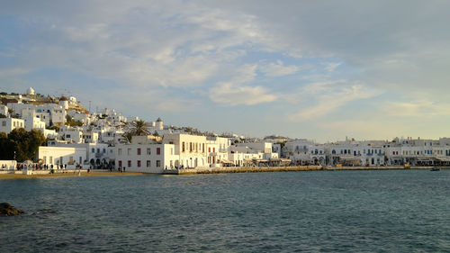 Buildings by river against sky