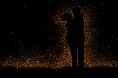 Silhouette people standing on field at night