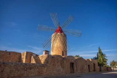 Low angle view of traditional windmill against blue sky