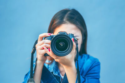 Portrait of woman photographing against blue sky