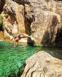 Side view of man on rock by water