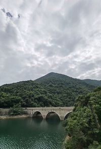 Arch bridge over mountains against sky
