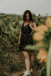 Young woman standing amidst sunflowers on field