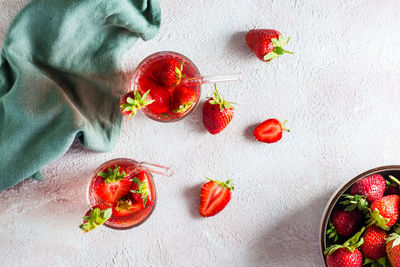 Refreshing cocktail with strawberries in glasses with a straw on the table and a bowl with berries.