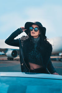 Young woman wearing sunglasses against airplane in vehicle on runway