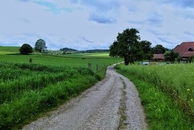 Road amidst field against sky