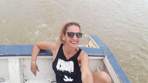 Portrait of smiling woman sitting in boat on sea