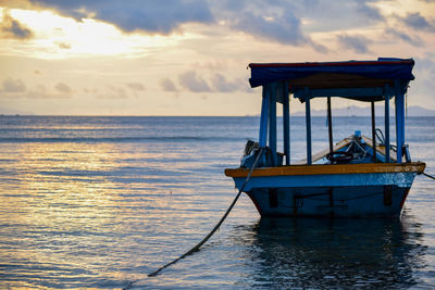 Boat moored on sea against sky during sunset