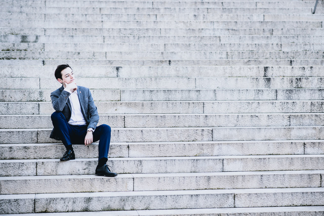 one man only, only men, one person, adults only, copy space, adult, sitting, businessman, mid adult, well-dressed, people, men, outdoors, business, young adult, handsome, one young man only, full length, suit, day, city