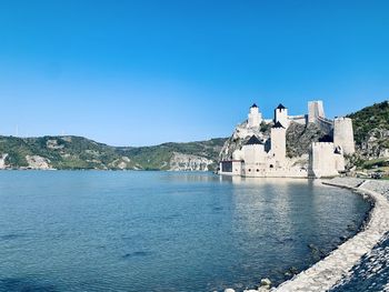 Buildings at waterfront against blue sky