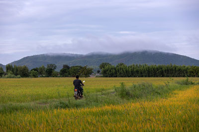 Rear view of woman walking on field against sky