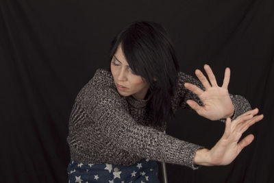 Woman gesturing against black backdrop