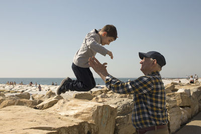 Side view of grandfather playing with grandson against clear sky