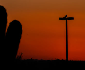 Silhouette cross against orange sky