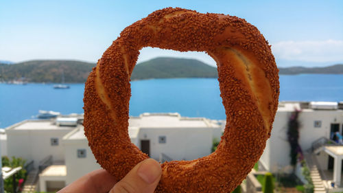 Close-up of person holding pretzel against sea