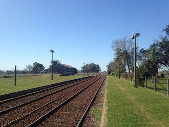 Railroad tracks on field against blue sky