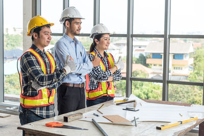 Architects standing by papers and work tools on desk at office