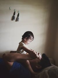 Father playing with daughter while lying on bed at home