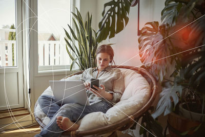 Woman using smart phone and laptop at home