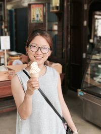 Portrait of happy woman showing ice cream cone in store