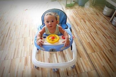 High angle portrait of cute baby boy in walker at home