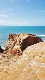 Rock formations on beach against sky