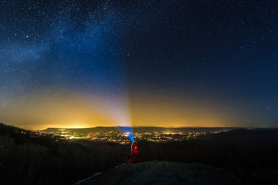 Rear view of person with flashlight against star field