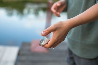 Midsection of boy holding fish on pier over lake