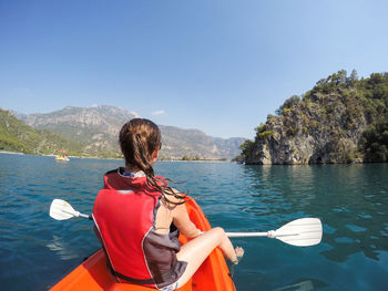 Rear view of woman canoeing in river