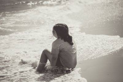Rear view of girl sitting at beach