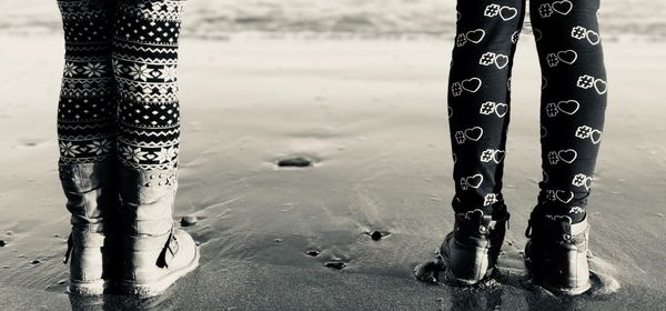 Low section of friends standing at beach