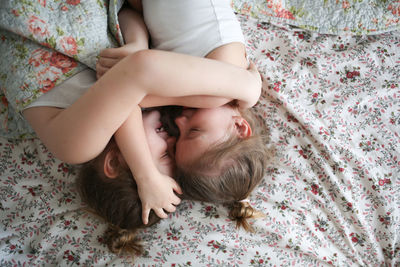 Sister's girls play and cuddle under a blanket, emotions. 